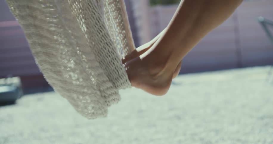 Womans feet on a hammock swaying back and forth outdoors