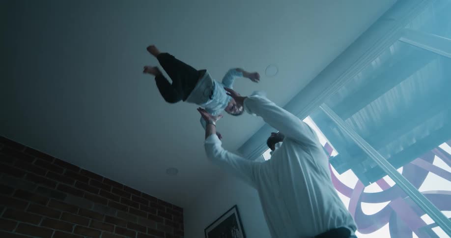 Father picking his son up from the ground and throwing him up in the air in a playful way