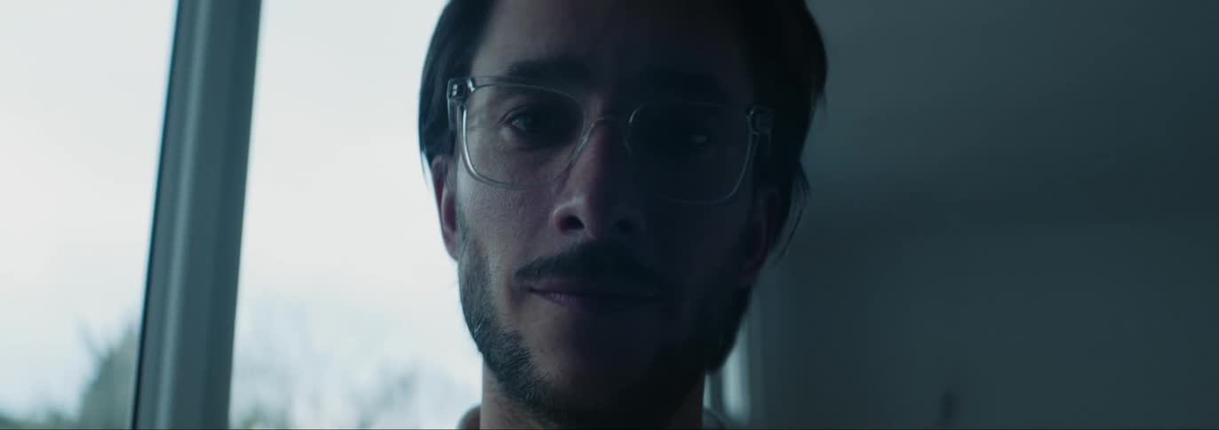 Adult man wearing glasses standing next to a glass window