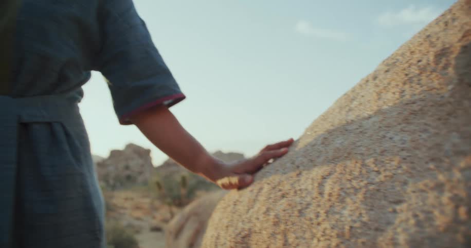 Latin woman standing outdoors in the nature touching a rock at a sunny day