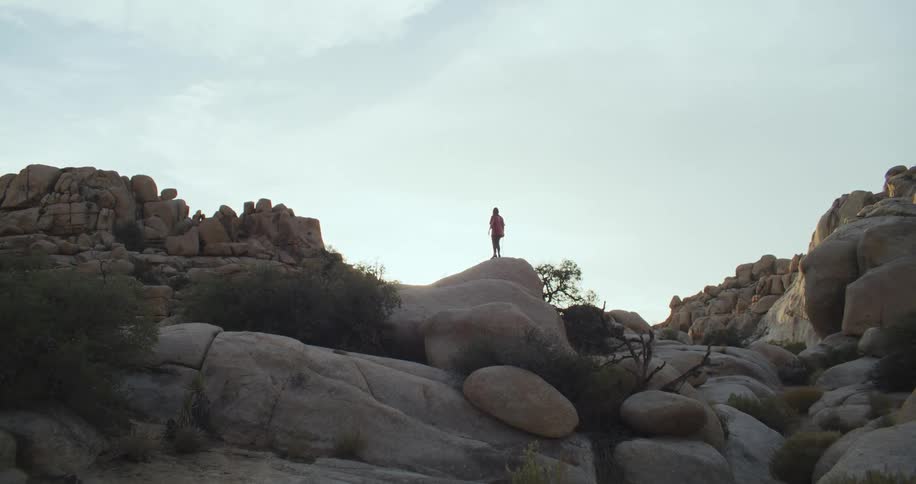A woman walks to the tip of a boulder in a canyon