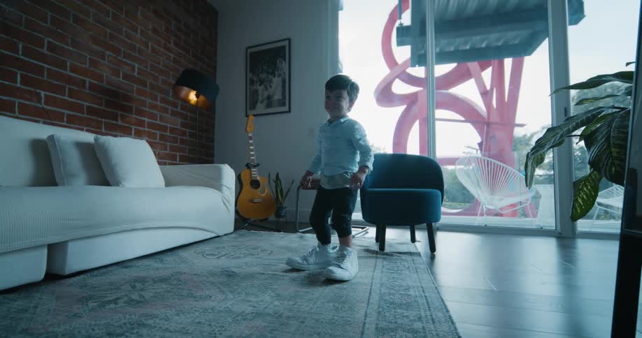 Two small boys wearing adult size shoes trying to walk around the living room