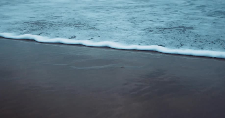 Ocean wave breaks against the sand on the beach