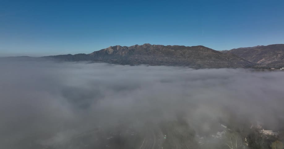 Fog covers area between tree surrounded mansions and mountains on the horizon