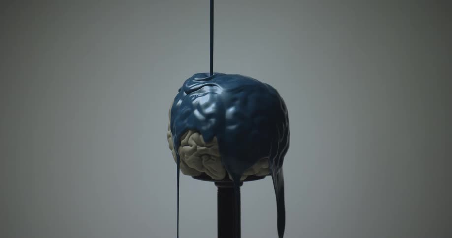 Blue paint being poured over a white brain mold on a pedestal