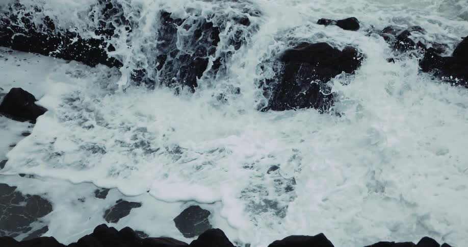 Foamy ocean waves crash against oceanside cliff