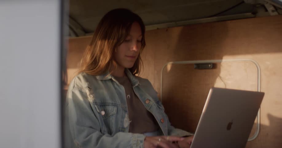 A woman sits in the back of her van and uses her laptop