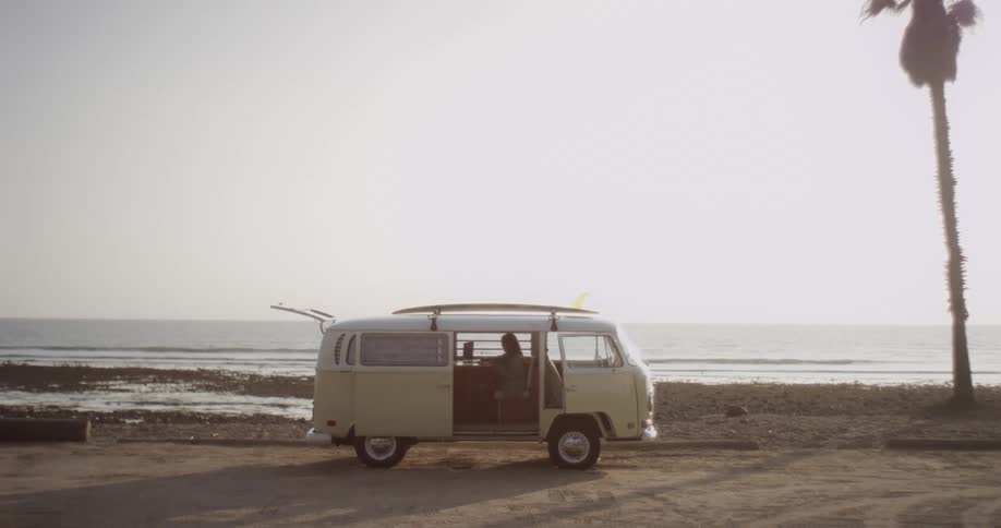 A woman sits in the back of her van while parked by the beach
