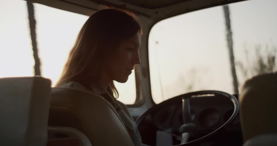 A woman sits in her parked van and uses her laptop