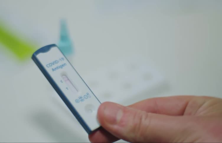 A man picks up a covid 19 negative test strip as a timer counts on a cell phone