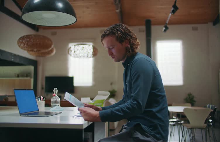 A young man removes the instruction sheet from a covid test box and nods as he reads