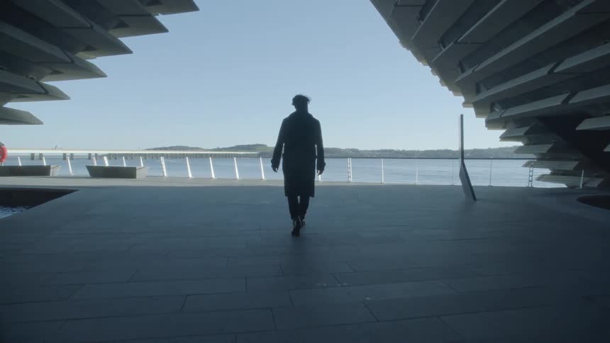 The silhouette of a man walking past a pool at the va dundee museum towards the ocean