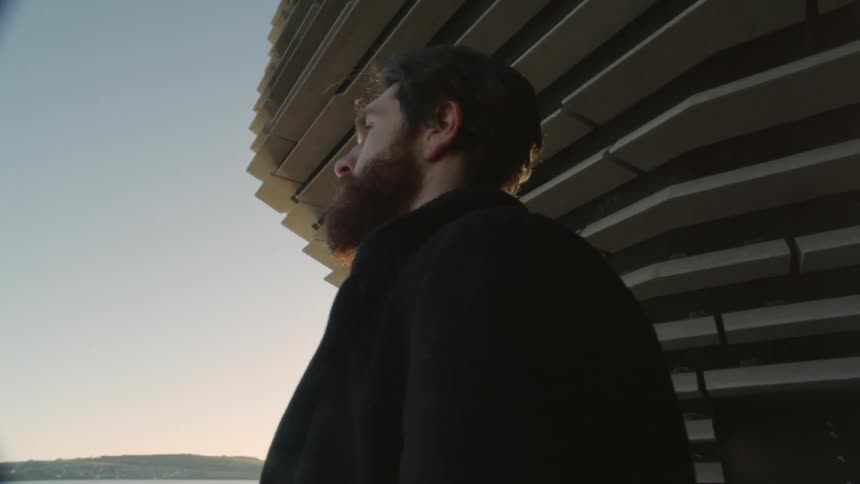 A man watches the sunset by the building