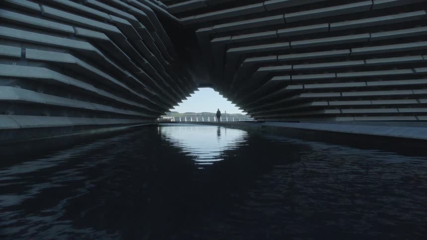 A person walking near water under a bridge