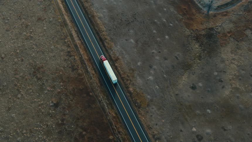 A semi trailer truck travels on a rural road