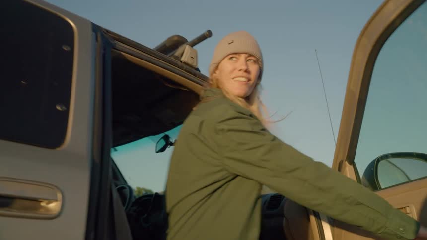 A woman climbs into the passenger side of a pickup truck