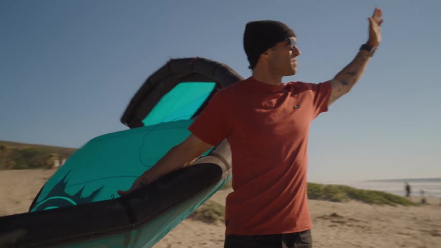 A man standing on the beach with a kite