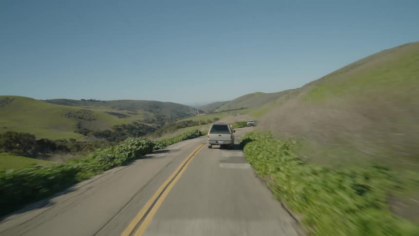 A pickup truck drives through the hills in spring