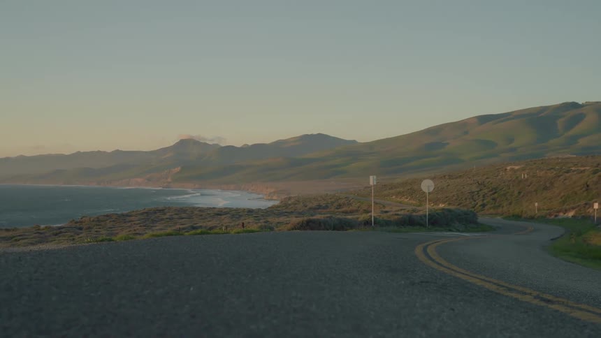 Gentle waves crash on the beach near a coastal road