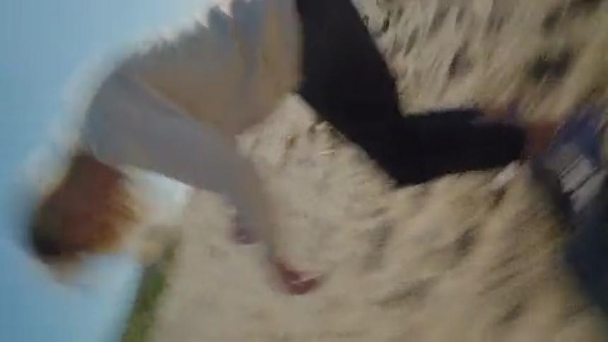 A woman does a backflip off a log into the sand