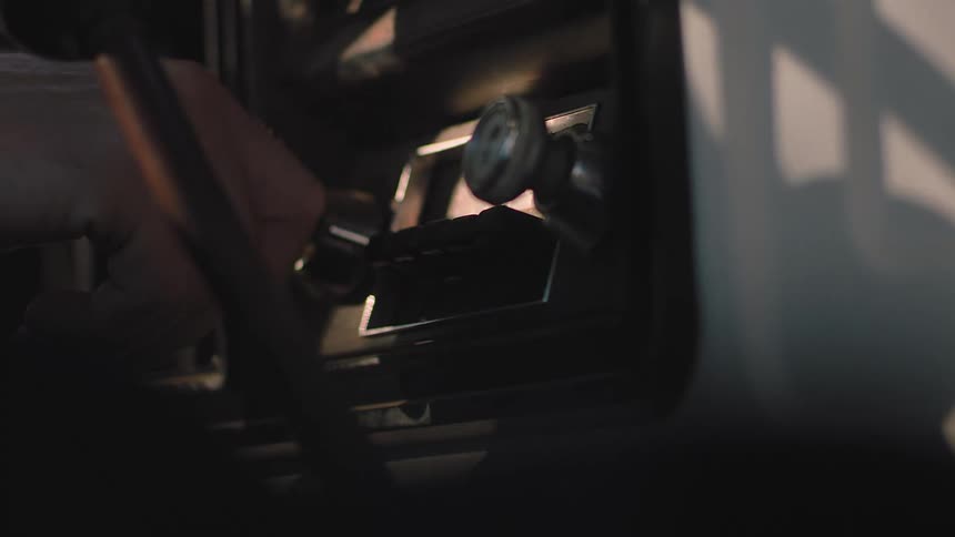 A hand presses a button and turns the knob on an old radio in a car dashboard