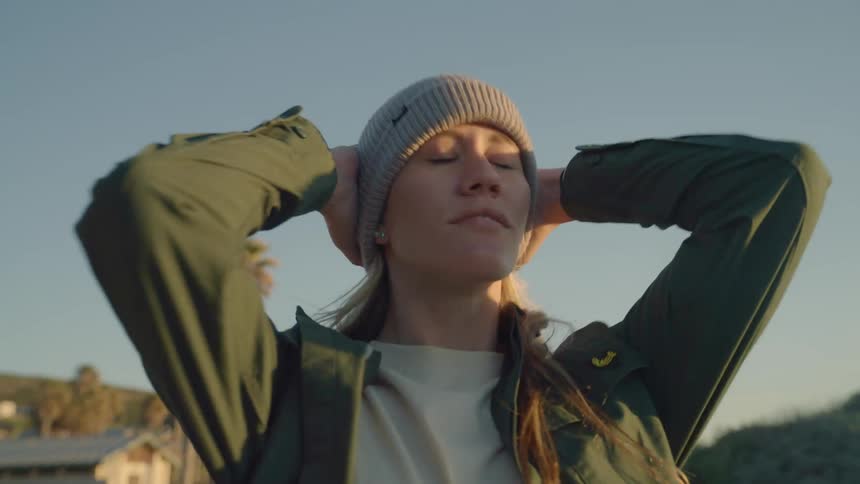 A woman putting on a beanie at the beach