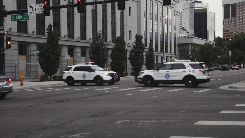 Traffic passes by police vehicles blocking off a road downtown