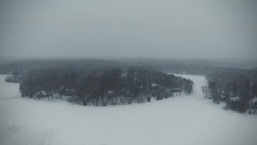 Aerial view of it snowing in a wooded area