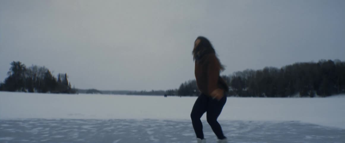 Young woman ice skating over a frozen lake in the snow covered field at winter