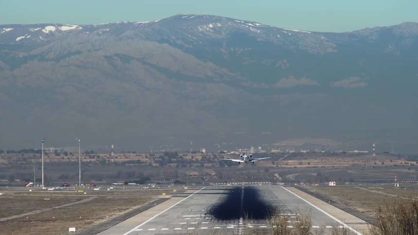 An airplane lands on the tarmac near a mountain range