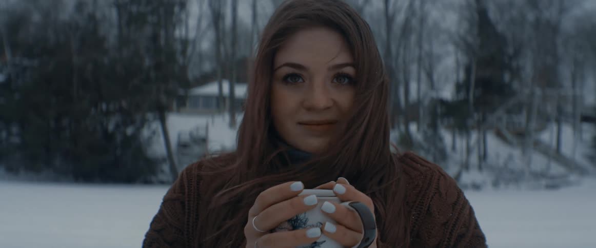 A woman stands outside in the cold of winter while posing for the camera