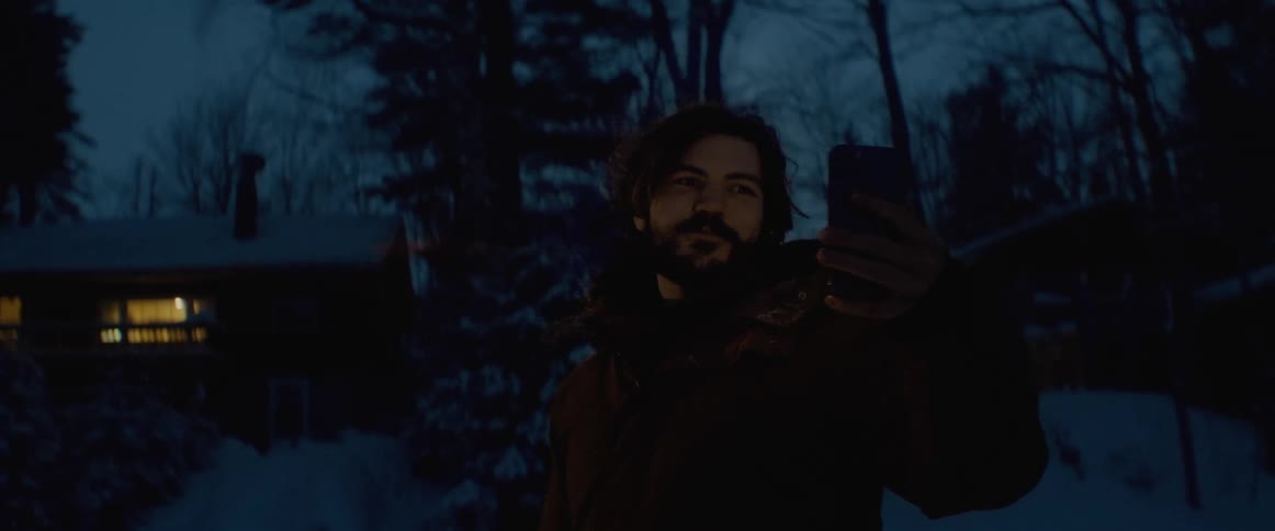 A man is outdoors talking on the phone in winter