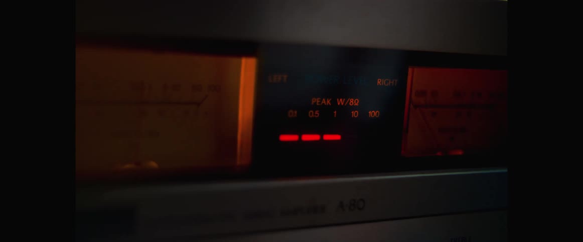 Lights blink and glow on audio equipment in a dark room