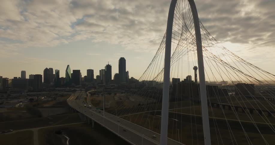 Cars are driving on a road near a downtown city at dusk