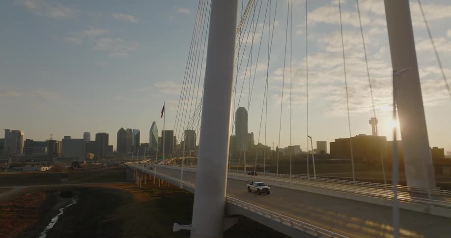 Cars travel over the margaret hunt hill bridge with the dallas skyline behind