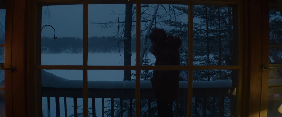 A view of a person standing on a balcony drinking from a mug