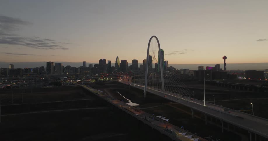 Aerial view of cars crossing the bridge and city skyline with skyscrapers at dusk