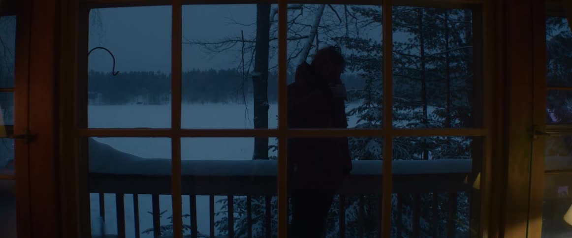A person is standing on a balcony outdoors in winter