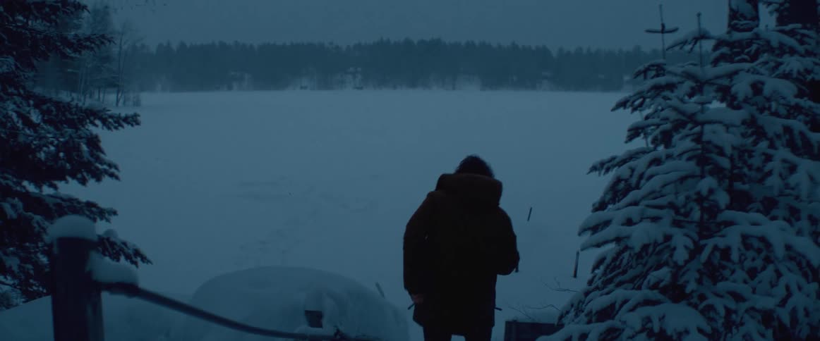 A man walks down a ramp to a frozen and snow covered lake
