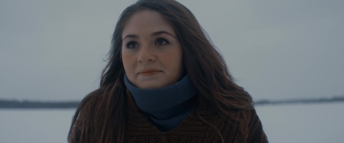 A girl is standing outdoors in winter and is shivering