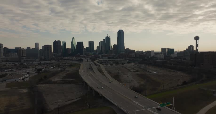 An aerial view of cars driving across an overpass with a city skyline in the distance