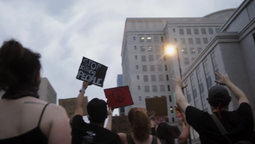People carry signs as they march downtown in protest