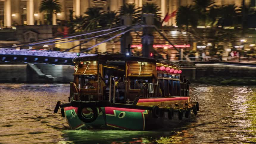 A colorful boat carrying tourists on a cruise of the singapore river at night