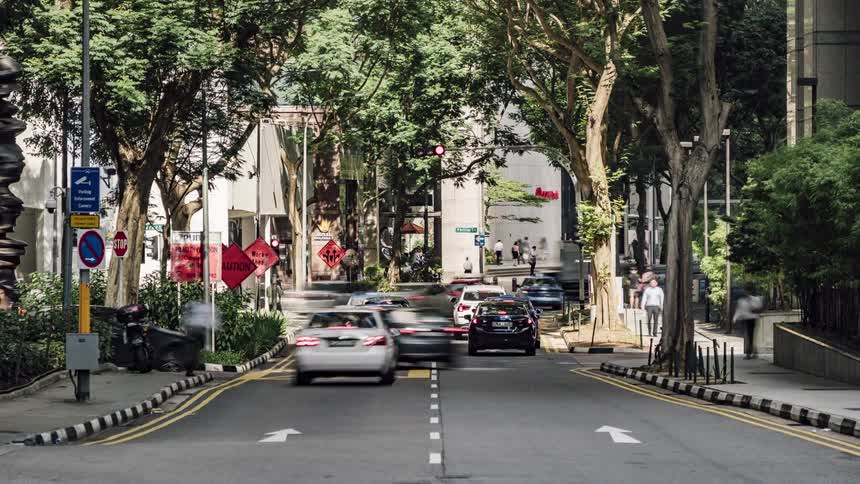 Pedestrians move along sidewalks as traffic flows through intersection