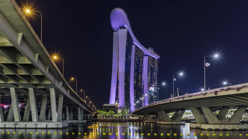 Colorful lights shine from buildings at marina bay reflecting on the river surface