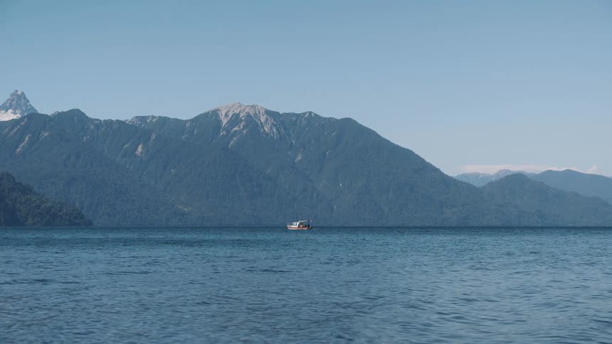 A boat passes a mountain range as it sails through the ocean