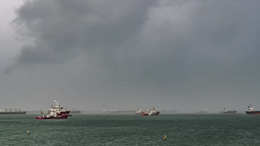 Ships and boats travel across water under dark clouds