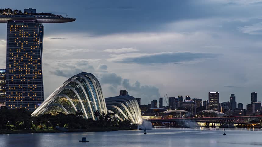 A time lapse of boats in the water in front of office buildings in a city with the skyline in the distance