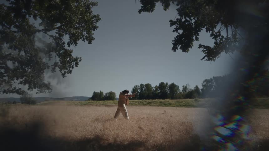A woman stretches to the side while dancing in a field