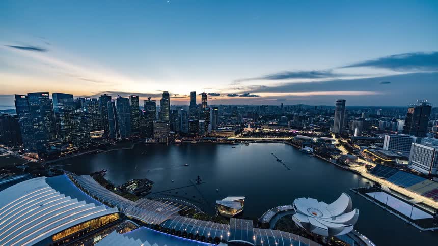 A time lapse of a city with office buildings in the skyline and boats in the water and cars driving down streets